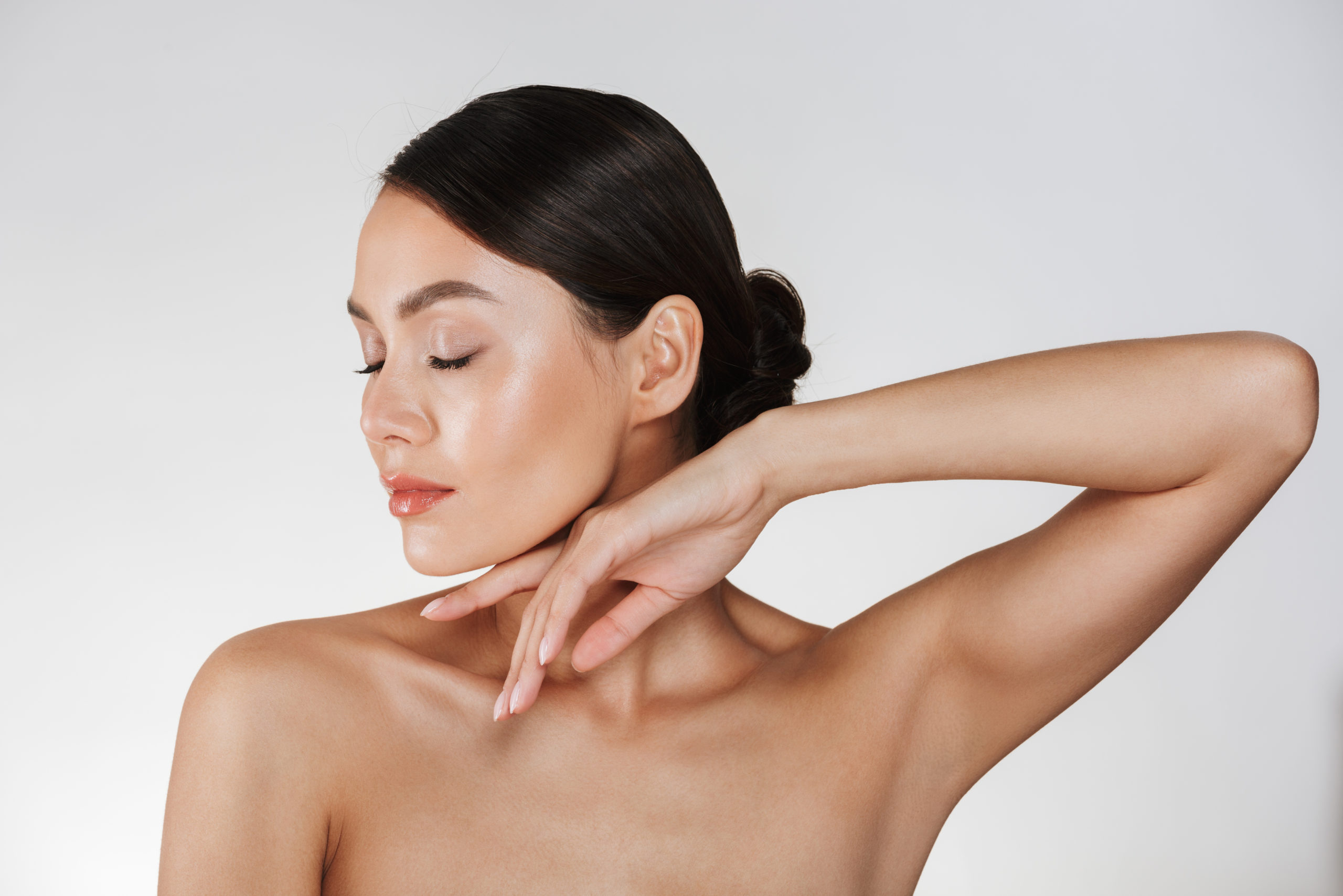 Close up studio portrait of brunette woman 20s with clean skin posing at camera with closed eyes isolated over white background
